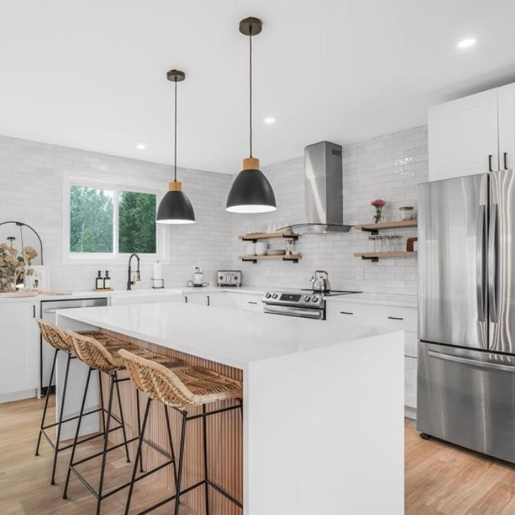 Modern kitchen with stainless steel appliances, white island, and wooden bar stools.