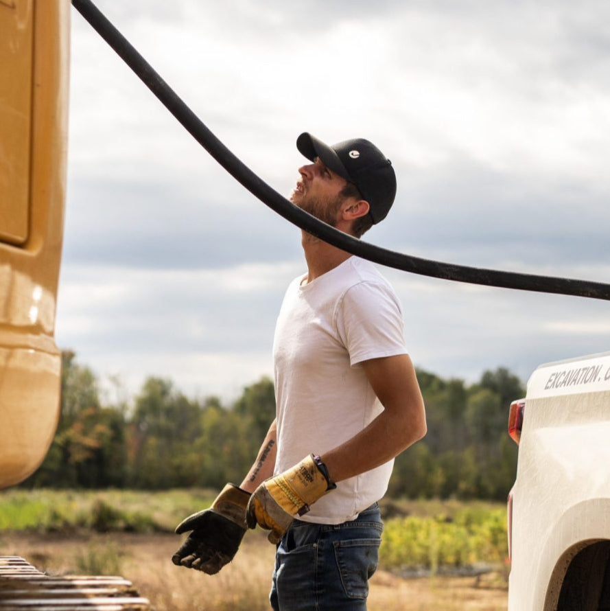 Man connecting a hose to a vehicle in an outdoor setting
